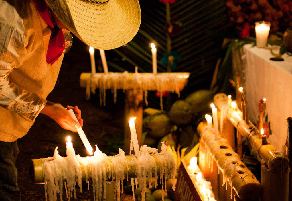 Niño en traje tradicional prendiendo velas en Festival de vida y muerte de Xcaret.