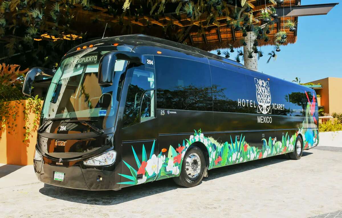 A black bus in front of a Hotel.