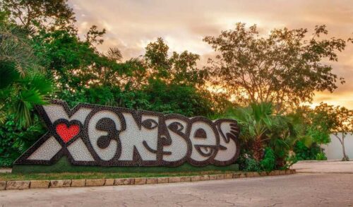 A stone sign that says Xenses, jungle and a sunset in the background.
